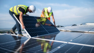 Bauarbeiter verlegen Solarpanele auf einem Dach